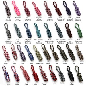 May include: A collection of 30 zipper pulls with various colors and patterns, including diamonds, camo, and stripes. The zipper pulls are made of cord and are designed to be used on bags, jackets, and other items.