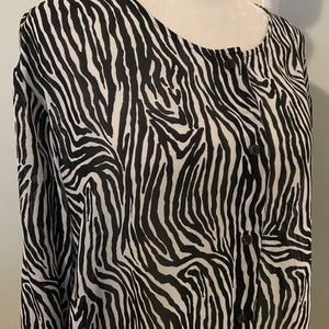 May include: A black and white zebra print button-up shirt with long sleeves.