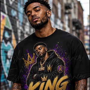 May include: Black t-shirt featuring a graphic of a man wearing a crown and the words "KING MINDSET" in gold and purple. The design includes a crown and the letter "K". The shirt has a crew neck and short sleeves.