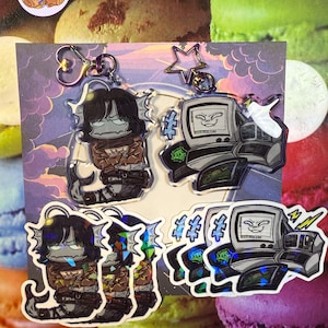 May include: Four acrylic keyrings. Two feature a cartoon character with black hair and a fish tail. The other two feature a cartoon computer with a face. All keyrings have a silver-coloured clasp.