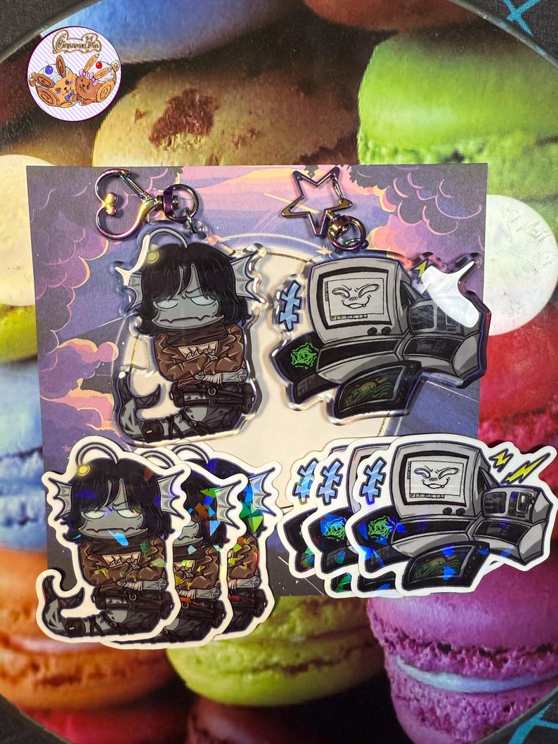 May include: Four acrylic keyrings. Two feature a cartoon character with black hair and a fish tail. The other two feature a cartoon computer with a face. All keyrings have a silver-coloured clasp.