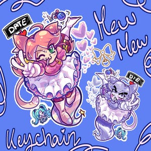 Op de afbeelding: Een digitale illustratie met twee katachtige personages in outfits met ruches op een blauwe achtergrond. Eén personage is roze, de andere paars, beide hebben kattenoren en staarten. Tekst: DATE, DIE, Mew Mew, Keychain. Inclusief een gouden strikbedel.