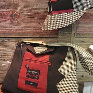May include: A handmade bag and hat set. The bag is made from a dark brown fabric with a red pocket and a houndstooth pattern. The hat is red and houndstooth with a black band. The bag has the text "Craig Scott".