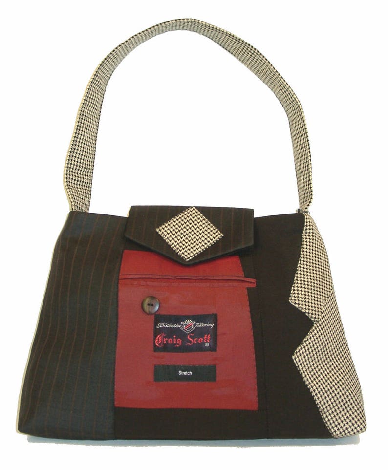 May include: A unique handbag with a houndstooth handle and accents. The bag features a red pocket with a button and a label that reads "Craig Scott". The bag is made from pinstripe and solid black fabric.