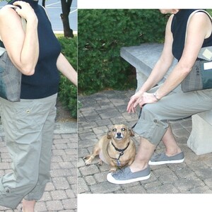 May include: A shoulder bag with a plaid and green design. The bag has a cream-colored strap and a pocket on the front. The person in the image is wearing a black top and khaki pants. A small dog is also in the image.