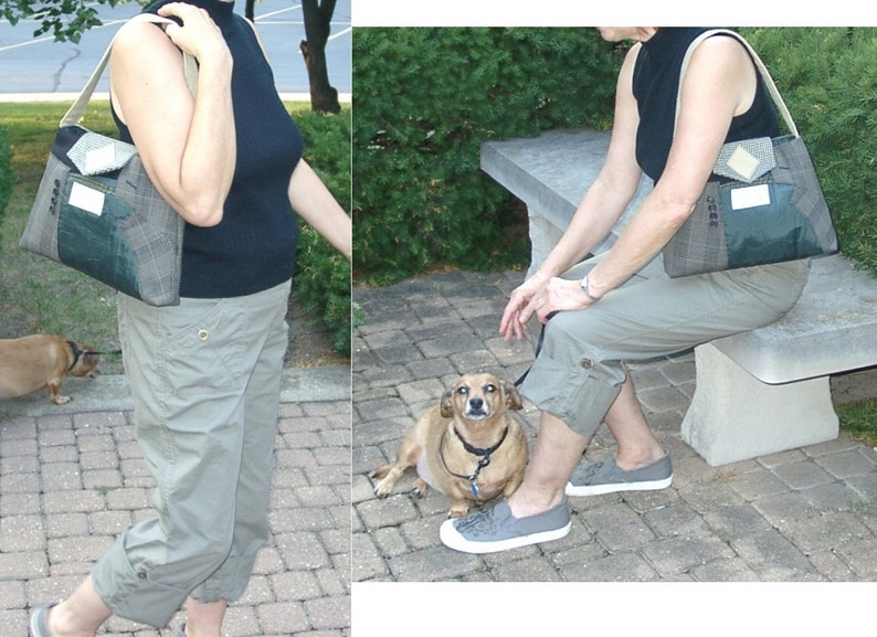 May include: A shoulder bag with a plaid and green design. The bag has a cream-colored strap and a pocket on the front. The person in the image is wearing a black top and khaki pants. A small dog is also in the image.