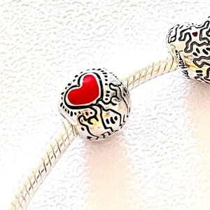 Herzförmiger Anhänger mit Keith-Haring-Motiven, geeignet für Pandora-Armbänder oder andere Marken.