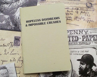 May include: A small, light green notebook with the text "HOPELESS DAYDREAMS & IMPOSSIBLE CRUSHES" printed in black on the front cover.