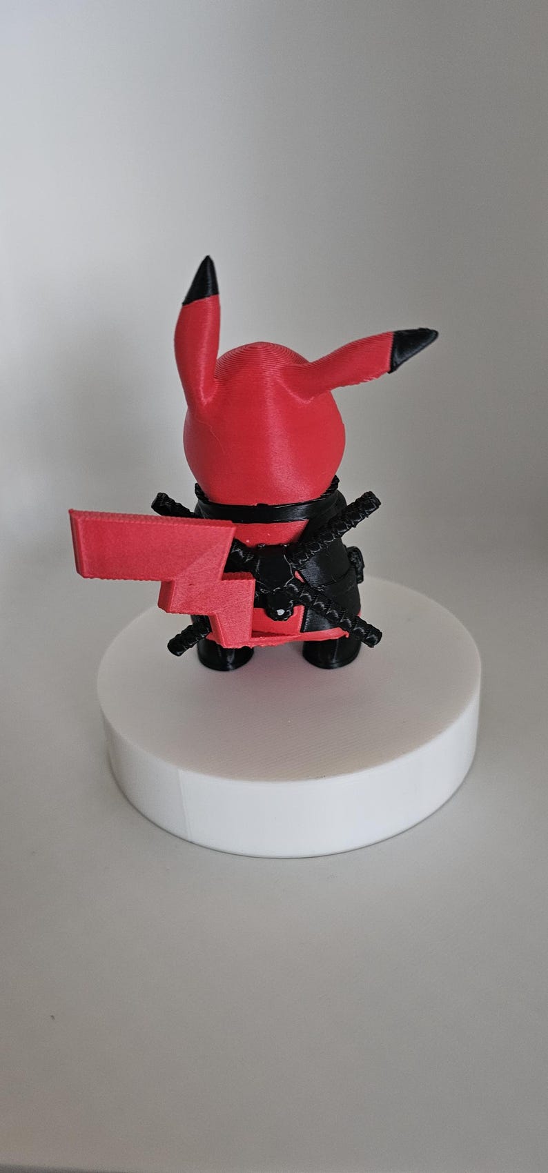 Puede incluir: Una figura de Pokemon impresa en 3D de color rojo y negro. El personaje sostiene una espada roja en su mano derecha y tiene un cintur&oacute;n negro alrededor de su cintura.