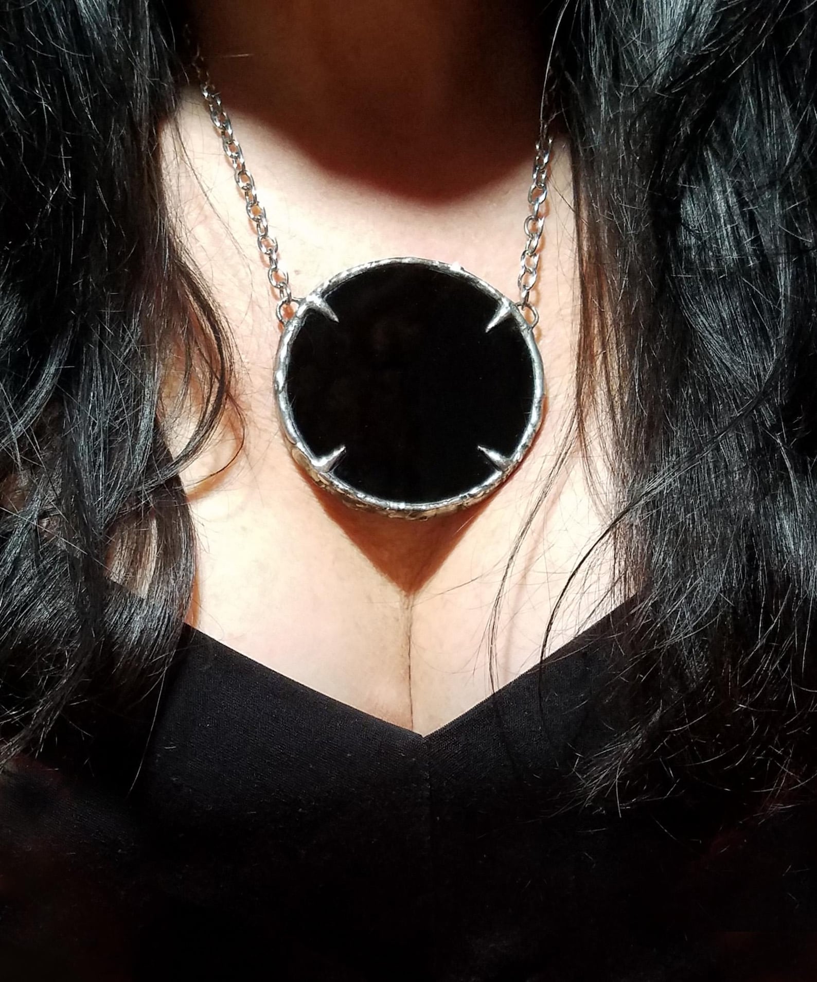 Woman wearing large black obsidian scrying necklace with claw prong setting and silver chain