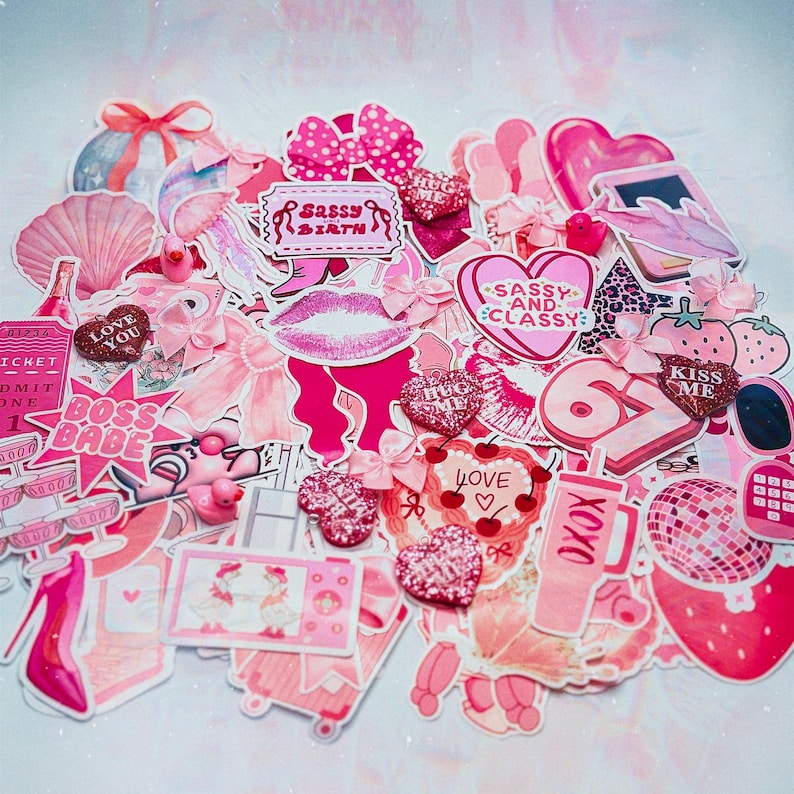 May include: A collection of pink stickers and embellishments, including hearts, bows, lips, and text that reads "Sassy Birth", "Boss Babe", "Love You", "Sassy and Classy", "Kiss Me", and "XOXO". The stickers vary in size and shape.