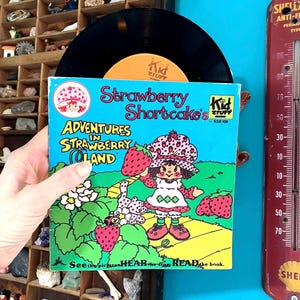 May include: A white ceramic mug with a black handle and the text "But First, Coffee" in a handwritten style. The mug is on a white surface. The mug is 4 inches tall.