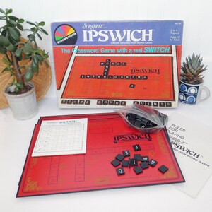 May include: A vintage Scrabble Ipswich crossword game set. The box is blue and red, with the game board and tiles visible. The game includes a red game board, black letter tiles, and instructions. The game is designed for 2 to 4 players, ages 10 and up.