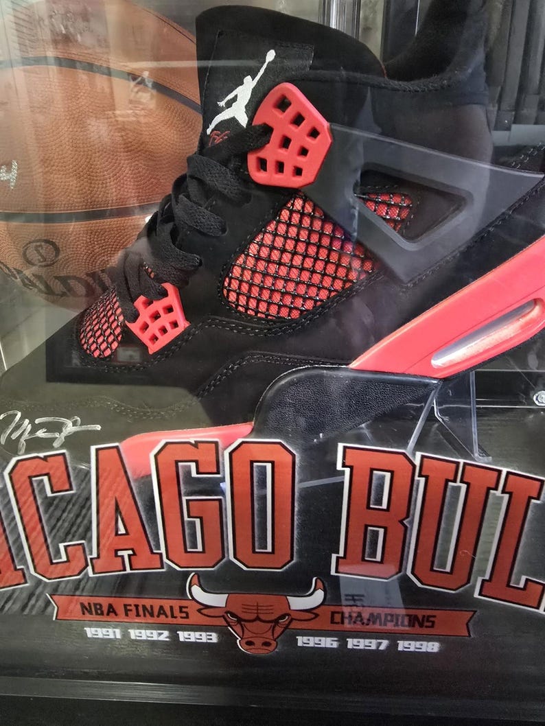 May include: Black and red Air Jordan basketball shoes in a display case with a basketball and the text "Chicago Bulls" and "NBA Finals 1991 1992 1993 Champions 1996 1997 1998".