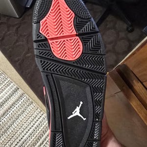 May include: Black and red basketball shoe with a white Jumpman logo on the sole.