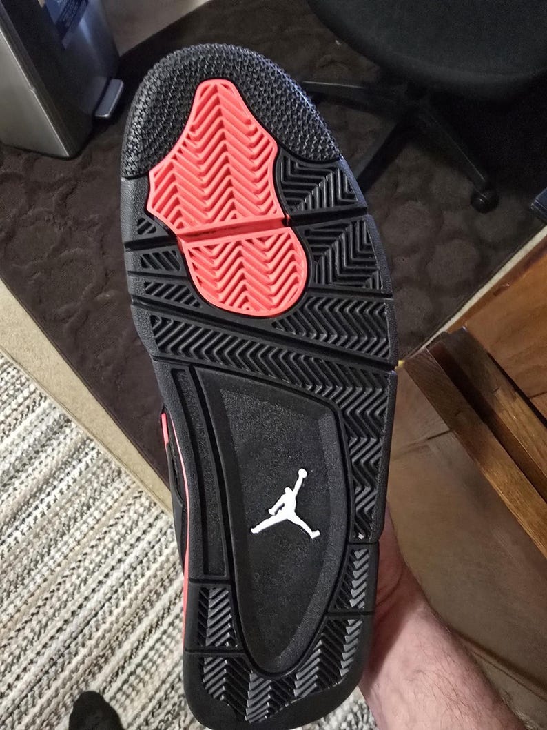 May include: Black and red basketball shoe with a white Jumpman logo on the sole.