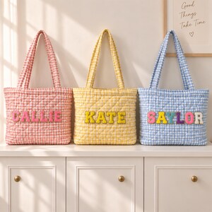 May include: Three quilted tote bags in pink, yellow, and blue gingham patterns. Each bag features two shoulder straps and a personalized name patch on the front. The pink bag reads CALLIE, the yellow bag reads KATE, and the blue bag reads SAYLOR.