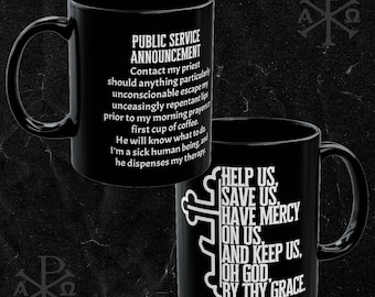 Op de afbeelding: Zwarte keramische koffiemok met een wit ontwerp. De mok heeft een publieksdienstmededeling over het contacteren van een priester en een religieus citaat. Het citaat luidt "Help ons, red ons, wees genadig voor ons, en bewaar ons, o God, door uw genade."