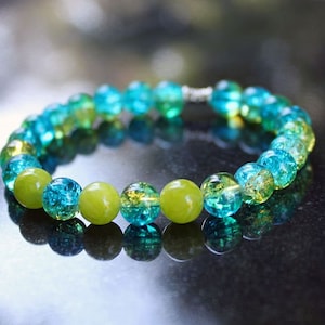 May include: A green and blue glass bead bracelet with a silver clasp. The beads are round and have a textured surface.