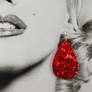 May include: A pair of red glitter teardrop earrings with silver hooks.