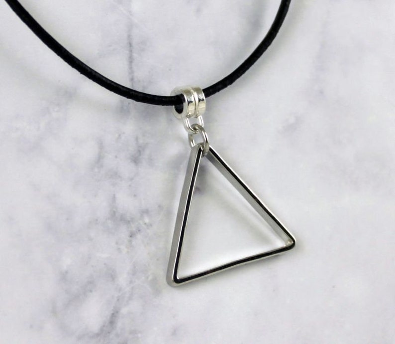 May include: A silver triangle pendant necklace with a black leather cord.