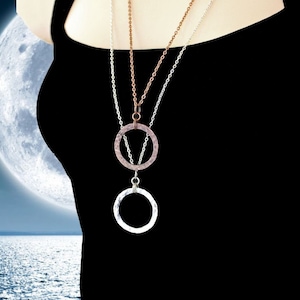 May include: Three layered necklaces with hammered metal circle pendants. The top pendant is rose gold, the middle is silver, and the bottom is silver.
