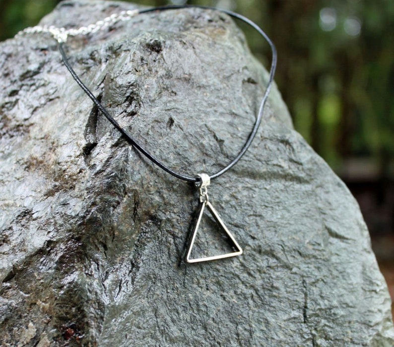 May include: A simple silver triangle pendant necklace on a black leather cord.