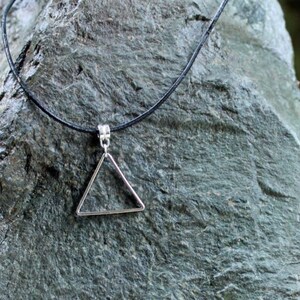 May include: A simple silver triangle pendant necklace on a black cord.