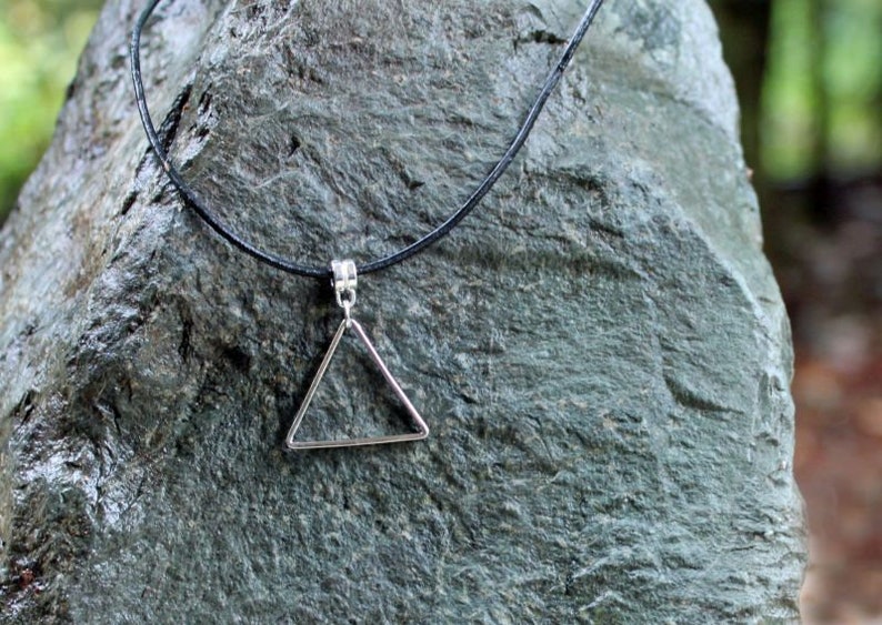 May include: A simple silver triangle pendant necklace on a black cord.