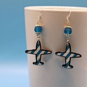 May include: A pair of silver earrings with blue glass beads and airplane charms. The airplanes are black with white stripes.
