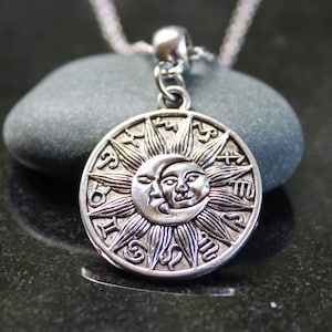 May include: Silver necklace with a round pendant featuring a sun and moon design with zodiac symbols around the edge.