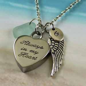 May include: Silver necklace with a heart charm engraved with the words "Always in my Heart", a small sea glass charm, and a silver angel wing charm with a small silver disc charm with the letter "G" engraved on it.