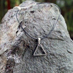 May include: A black leather choker necklace with a silver triangle pendant.