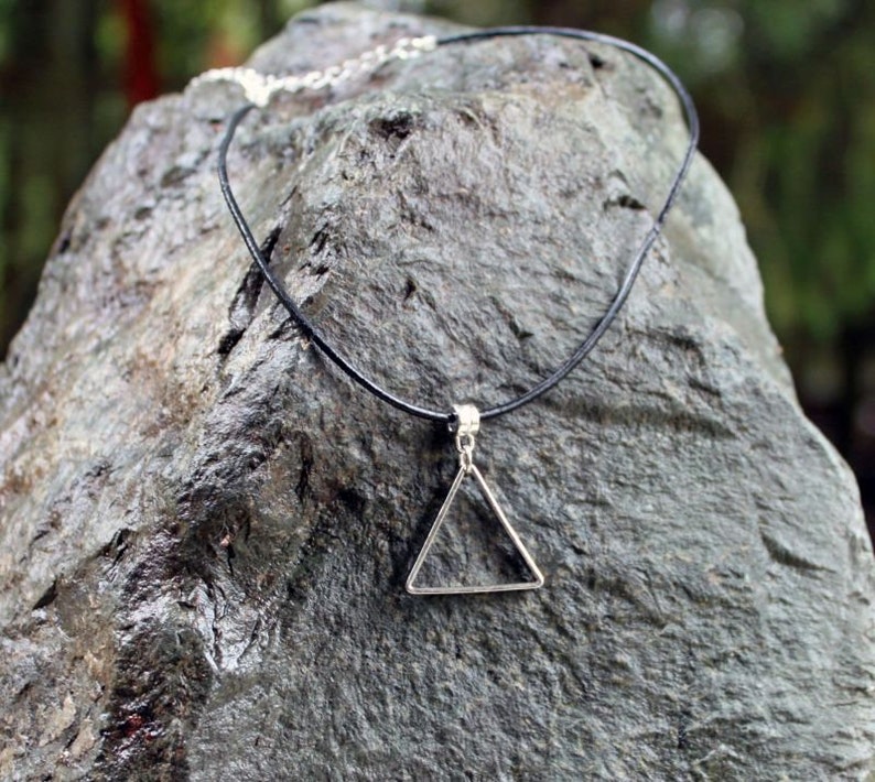 May include: A black leather choker necklace with a silver triangle pendant.