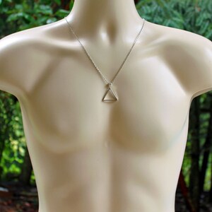 May include: A silver chain necklace with a simple triangle pendant.