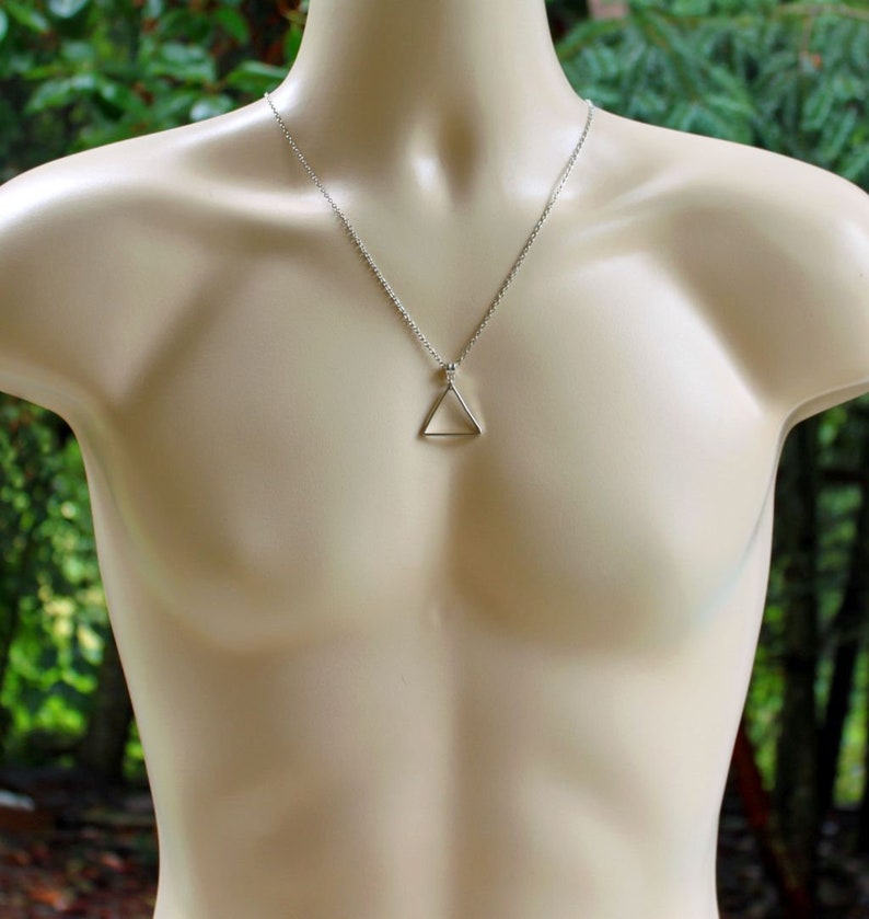 May include: A silver chain necklace with a simple triangle pendant.