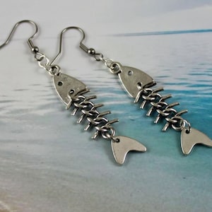 May include: Silver fishbone earrings with a chain link design. The earrings are on a white background.