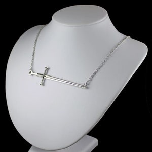 May include: A silver necklace with a sword pendant. The sword is a simple design with a straight blade and a cross guard.