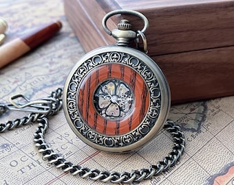 May include: Antique pocket watch with a silver-tone case, a decorative bezel, and a wooden-look face. The watch features a visible mechanical movement and is attached to a silver chain. The watch is displayed on a vintage map.
