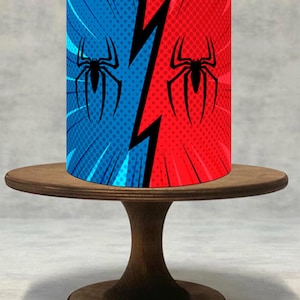 Könnte beinhalten: Ein zylindrischer Tortenständer mit Comic-Design. Der Ständer ist in blaue und rote Hälften unterteilt und zeigt einen schwarzen Blitz und ein Spinnenlogo. Er steht auf einem hölzernen Tortenständer.