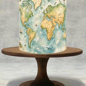 Può includere: Un paralume cilindrico con un design a mappa del mondo ad acquerello, che mostra i continenti in tonalità beige e verde su uno sfondo oceanico blu. Il paralume è posto su un alzatina per torte in legno marrone scuro.