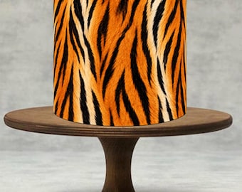 May include: A cylindrical cake featuring a vibrant orange and black tiger stripe pattern, positioned on a dark brown wooden cake stand with a circular base and a central pedestal support, showcasing a smooth texture and distinct animal print design.