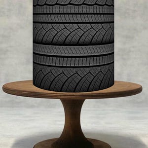以下が含まれることがあります： トレッドパターンが施された濃い灰色のタイヤのスタックが、小さくて丸い木製のテーブルの上に置かれています。 テーブルは台座ベースで、濃い茶色の仕上げです。 タイヤのスタックが主な焦点で、その詳細なデザインを示しています。