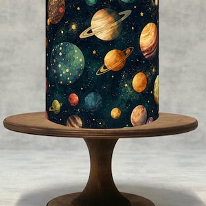 Könnte beinhalten: Ein zylindrischer Lampenschirm mit einem Aquarelldesign von Planeten, Sternen und Galaxien in Blau-, Orange- und Brauntönen. Der Lampenschirm steht auf einem runden Holztisch mit einem Sockel. Das Thema ist Weltraum und Astronomie.