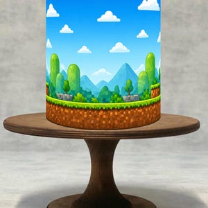 Peut inclure: Abat-jour cylindrique avec un motif de paysage pixélisé et vibrant, rappelant un jeu vidéo classique. Le design comprend un ciel bleu avec des nuages blancs, des collines vertes et un sol marron pixélisé. L'abat-jour est posé sur un présentoir à gâteau en bois brun foncé.