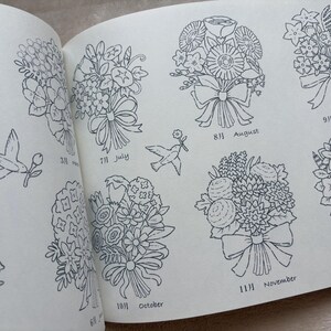 May include: A book open at a page featuring detailed line drawings of floral bouquets, each labeled with a month. Includes drawings of birds carrying flowers. The months August, September, October, November, and July are visible.