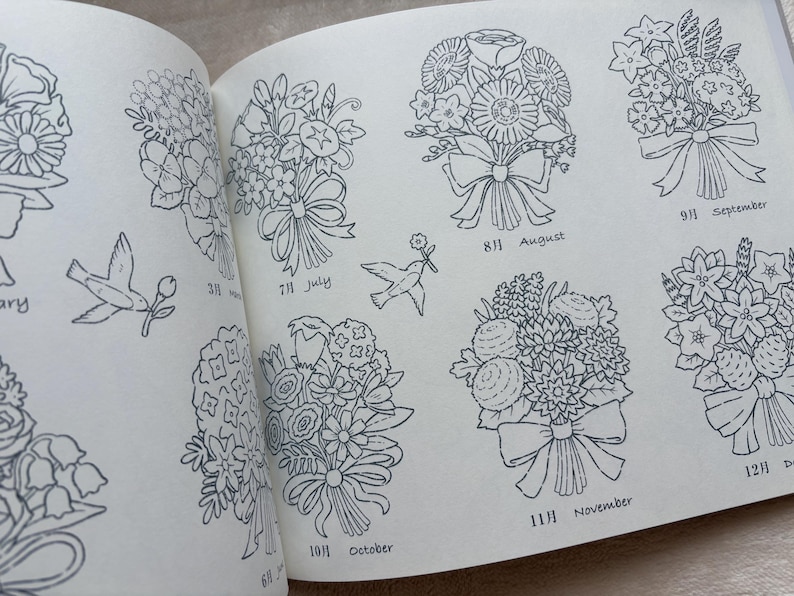 May include: A book open at a page featuring detailed line drawings of floral bouquets, each labeled with a month. Includes drawings of birds carrying flowers. The months August, September, October, November, and July are visible.