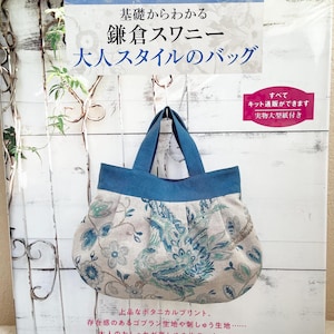 May include: A craft book titled "POMADOUR'S CRAFT BOOK" featuring a floral patterned handbag with blue handles. The book cover has Japanese text and a white background. The bag has a blue top and a floral design in shades of blue, green, and beige.