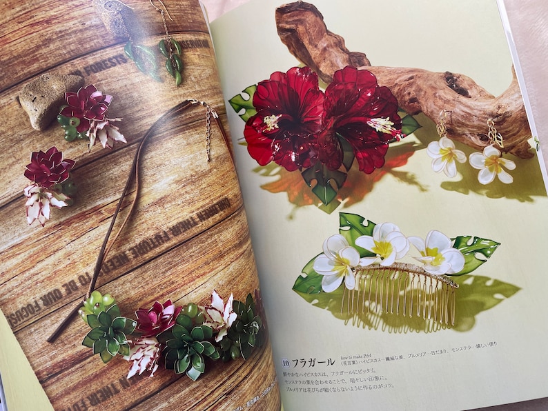 May include: A set of handmade jewelry featuring red hibiscus flowers, white plumeria flowers, and green leaves. The jewelry includes a necklace, earrings, and a hair comb.