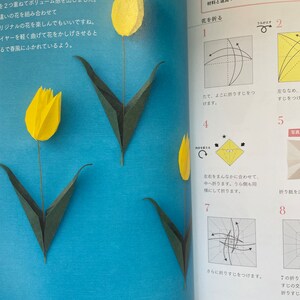 May include: A step-by-step guide on how to fold a paper origami tulip. The instructions are written in Japanese. The image shows a yellow origami tulip with green leaves.